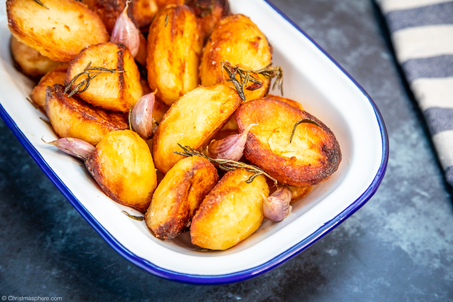 Close up of roasted potatoes with cloves of garlic and fresh rosemary