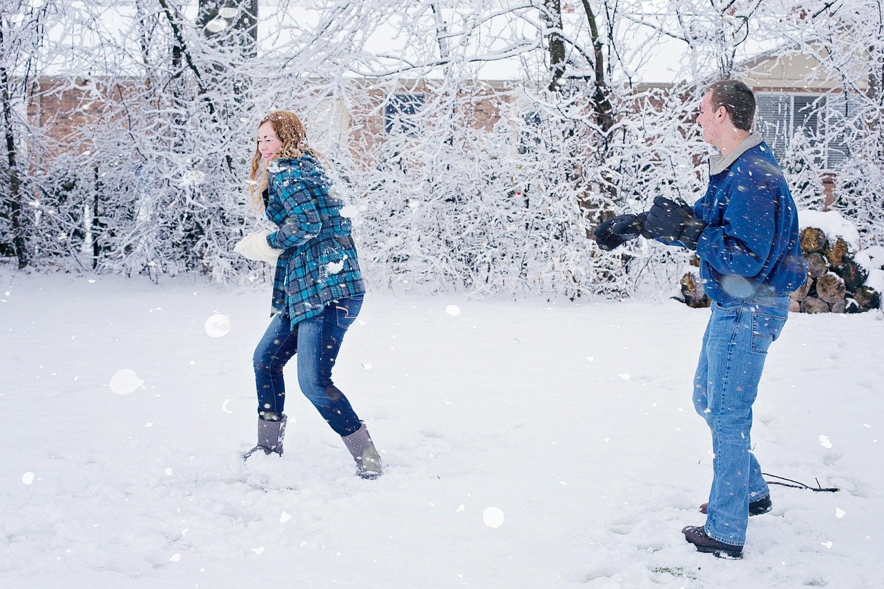 Boy throwing snowball at girl in snowball fight