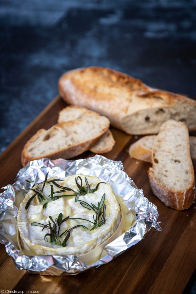 A wooden board of gooey baked camembert and crusty bread