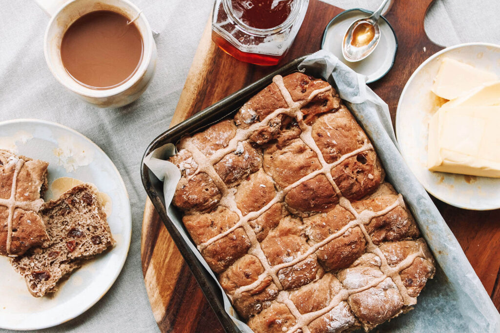 dish of hot cross buns and a cup of tea